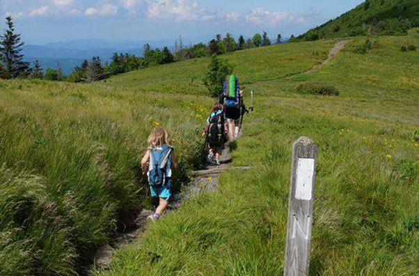Family of three hikes past white blaze
